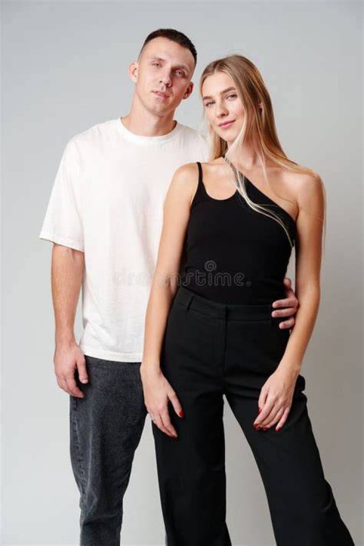 a woman standing next to a man wearing a black shirt and silver